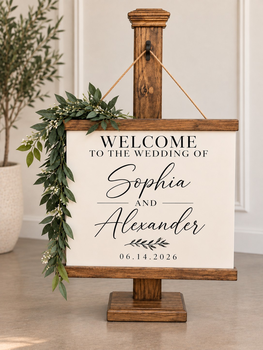 Personalized ivory wedding welcome sign hanging from a stained wooden post with greenery