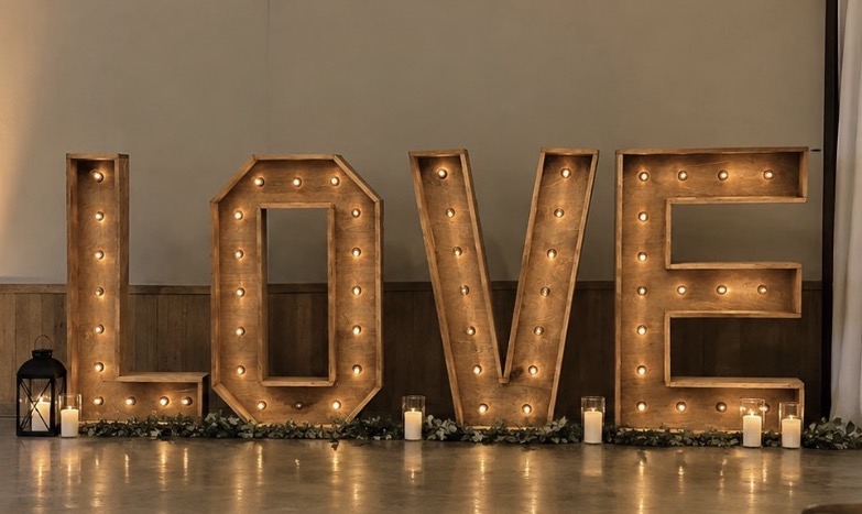 Four-foot illuminated LOVE letters styled with lanterns, candlelight, and greenery